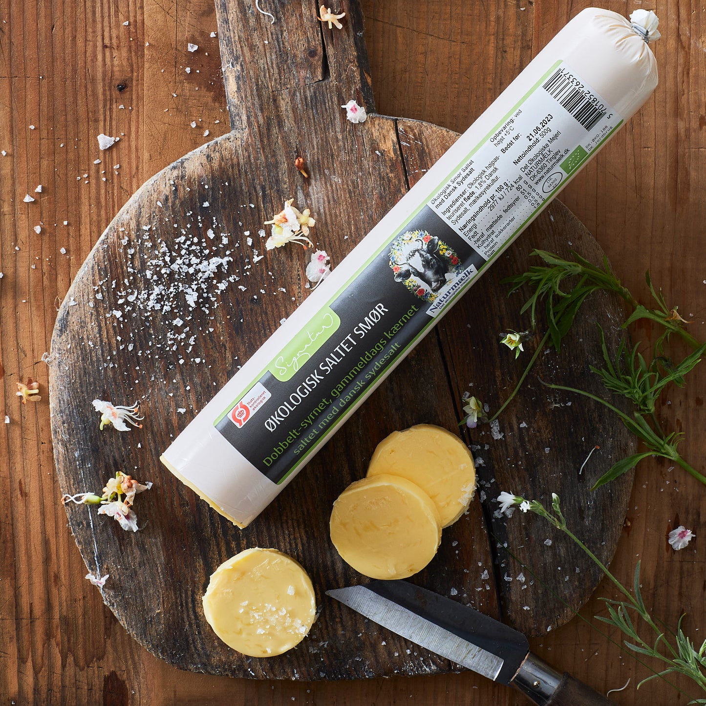 Økologisk saltet smør fra Naturmælk skåret på træbræt med urter