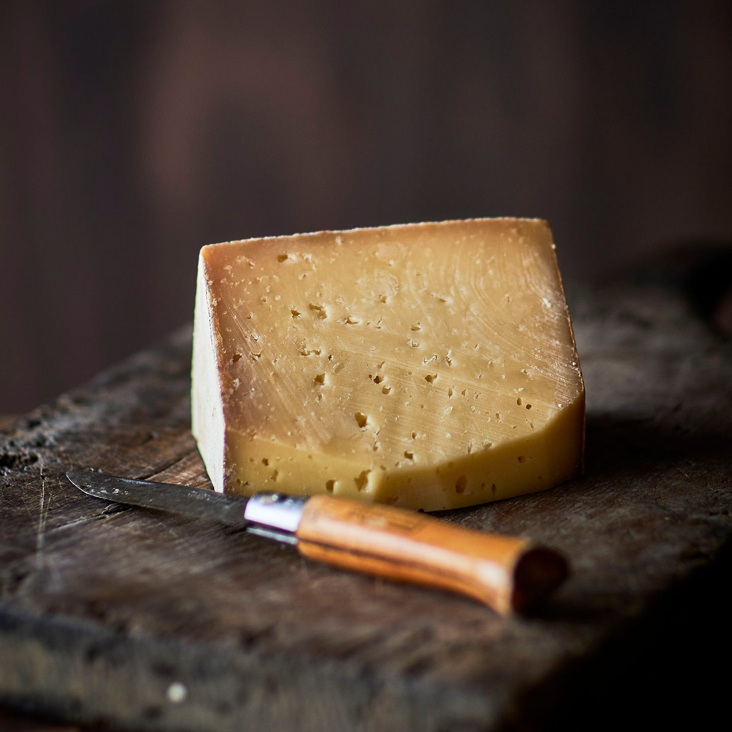 Modnet ostestykke på træbræt med ostekniv