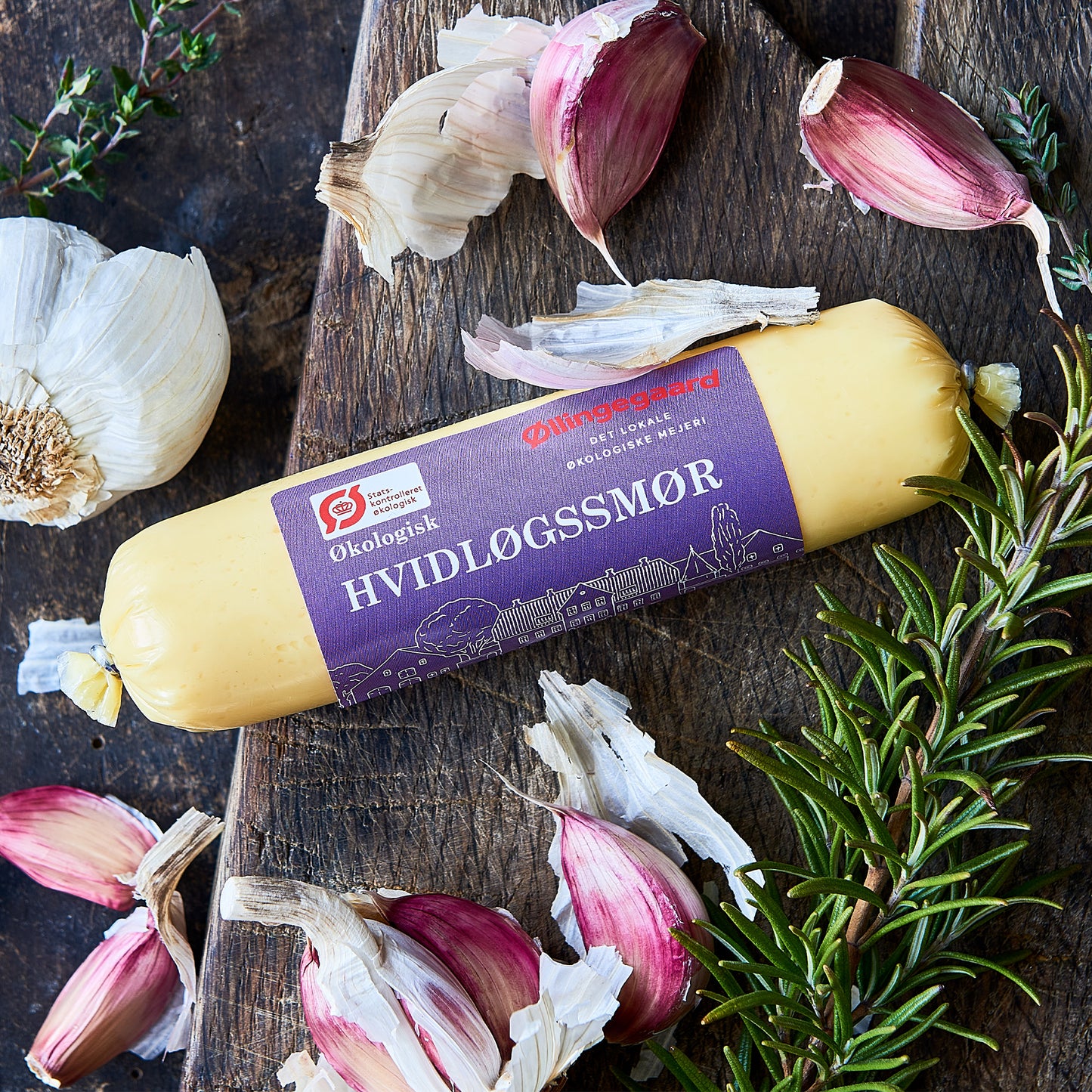 Økologisk hvidløgssmør med hvidløg og rosmarin på træbord