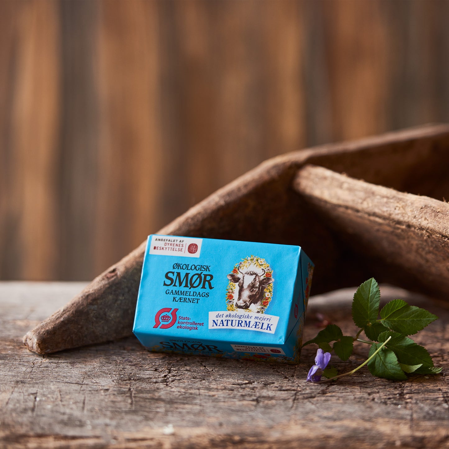 Økologisk smør gammeldags kærnet fra Naturmælk på træbaggrund med blomst
