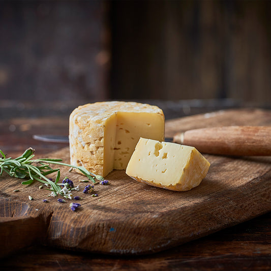 Modnet ost på skærebræt med rosmarin og lavendel