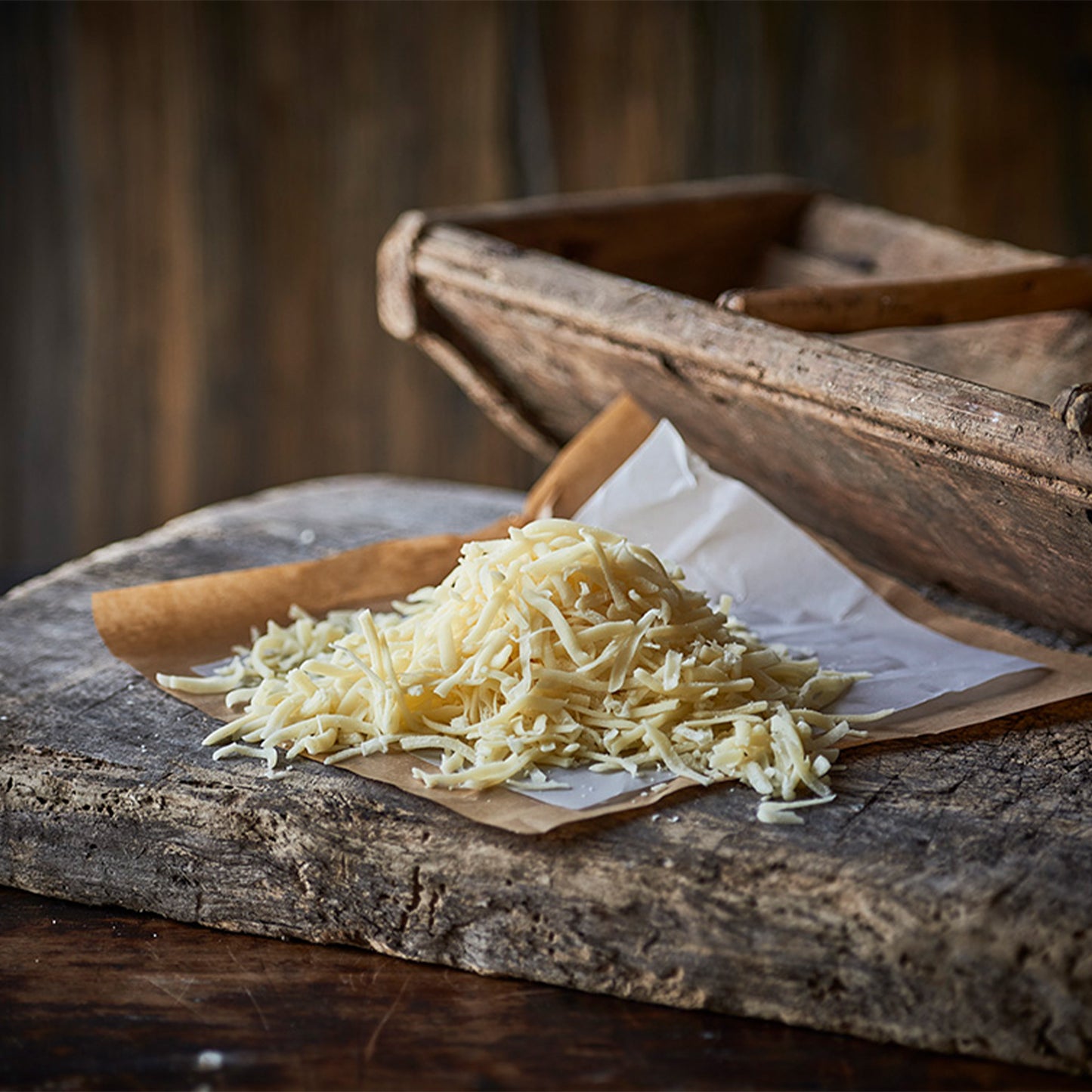Revet økologisk ost på papir ved træskål